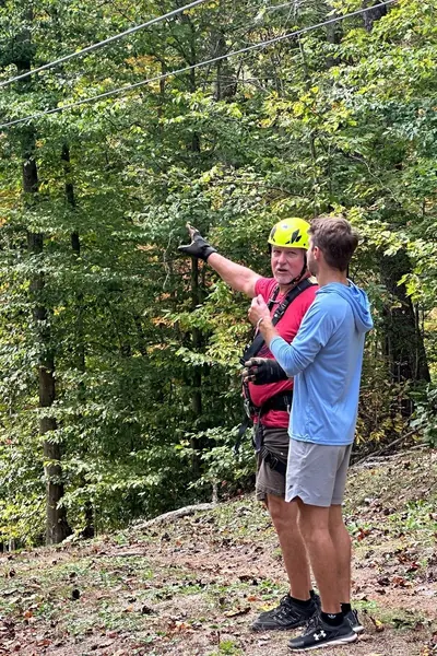 ARCL Innovations consultant discussing ropes course planning and site layout with a client at a wooded property.